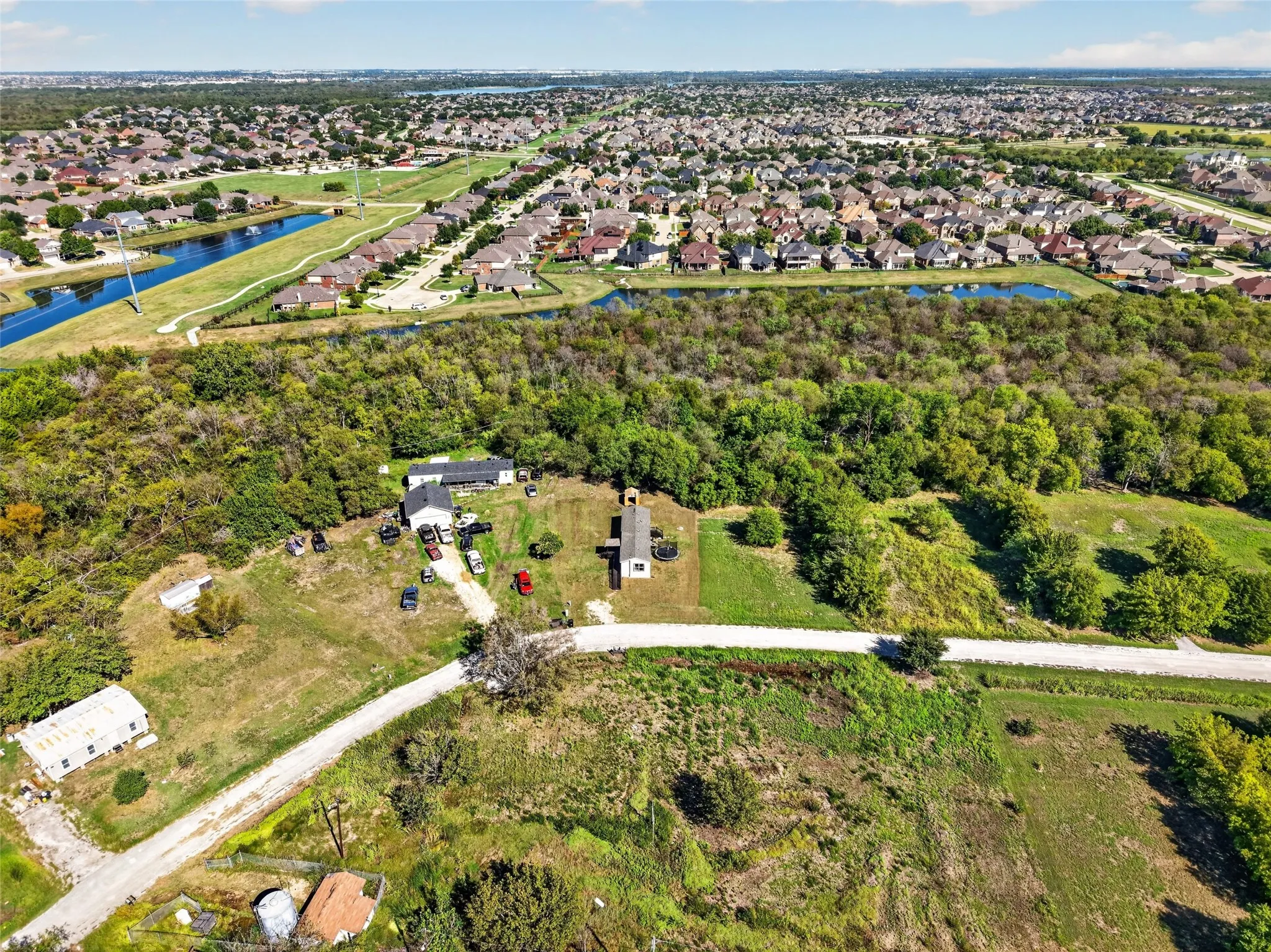 Expansive acreage with mature trees, two residential structures, and a gravel driveway