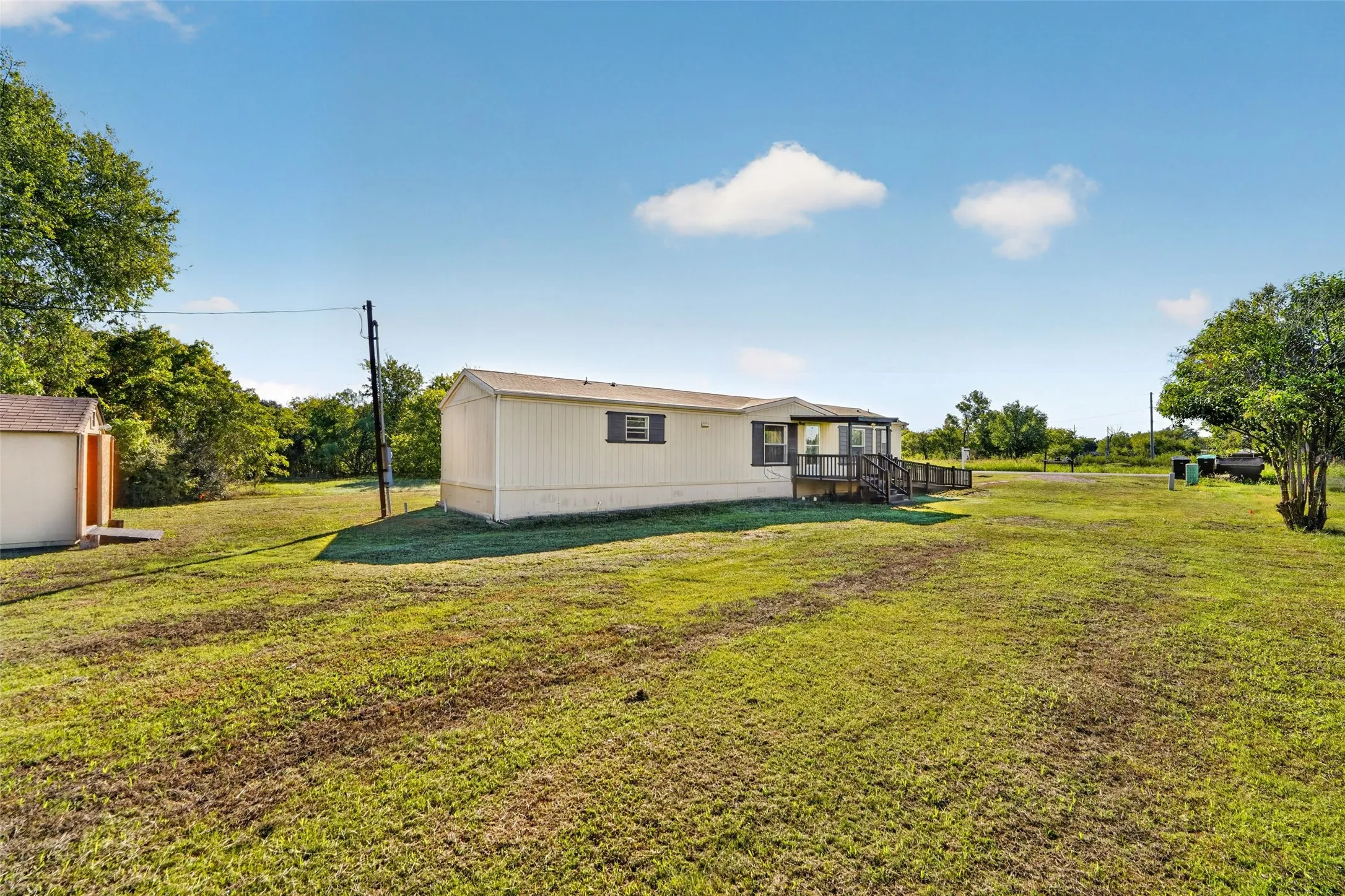 Expansive lawn with a detached storage shed, a covered front porch, and mature landscaping