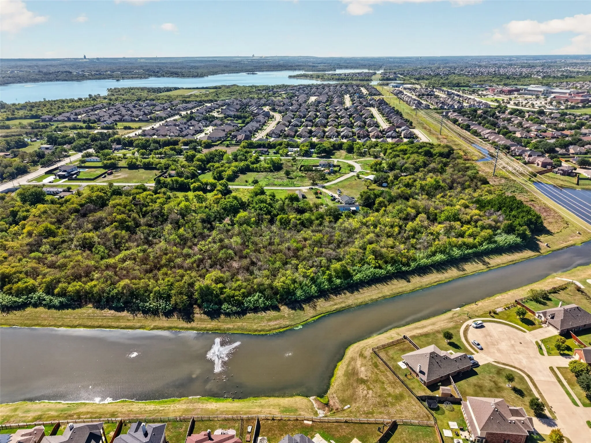 Expansive suburban landscape with a large body of water, established residential areas, and a tree-lined property