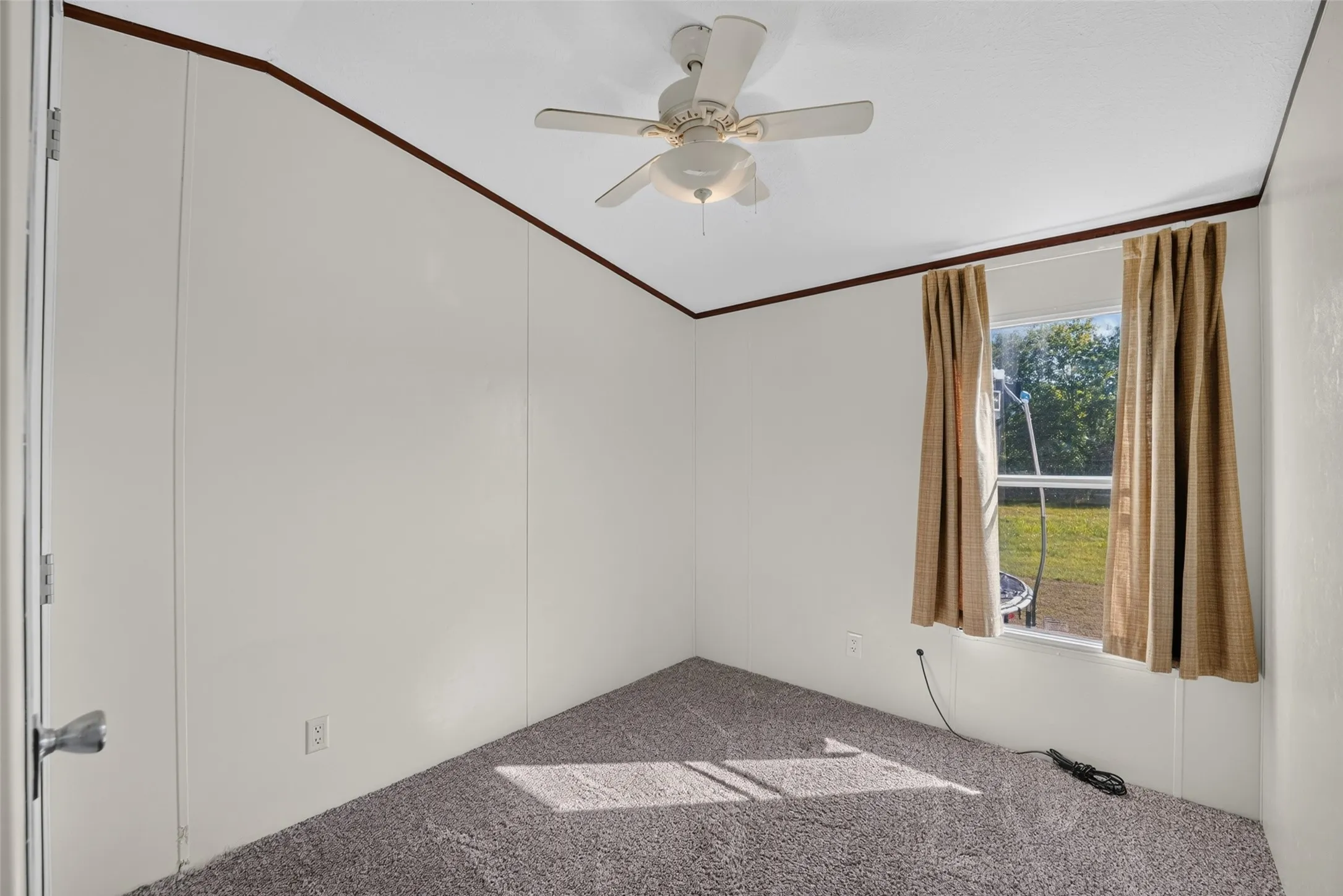 Ceiling fan with integrated lighting, window with drapes, and wall-to-wall carpeting