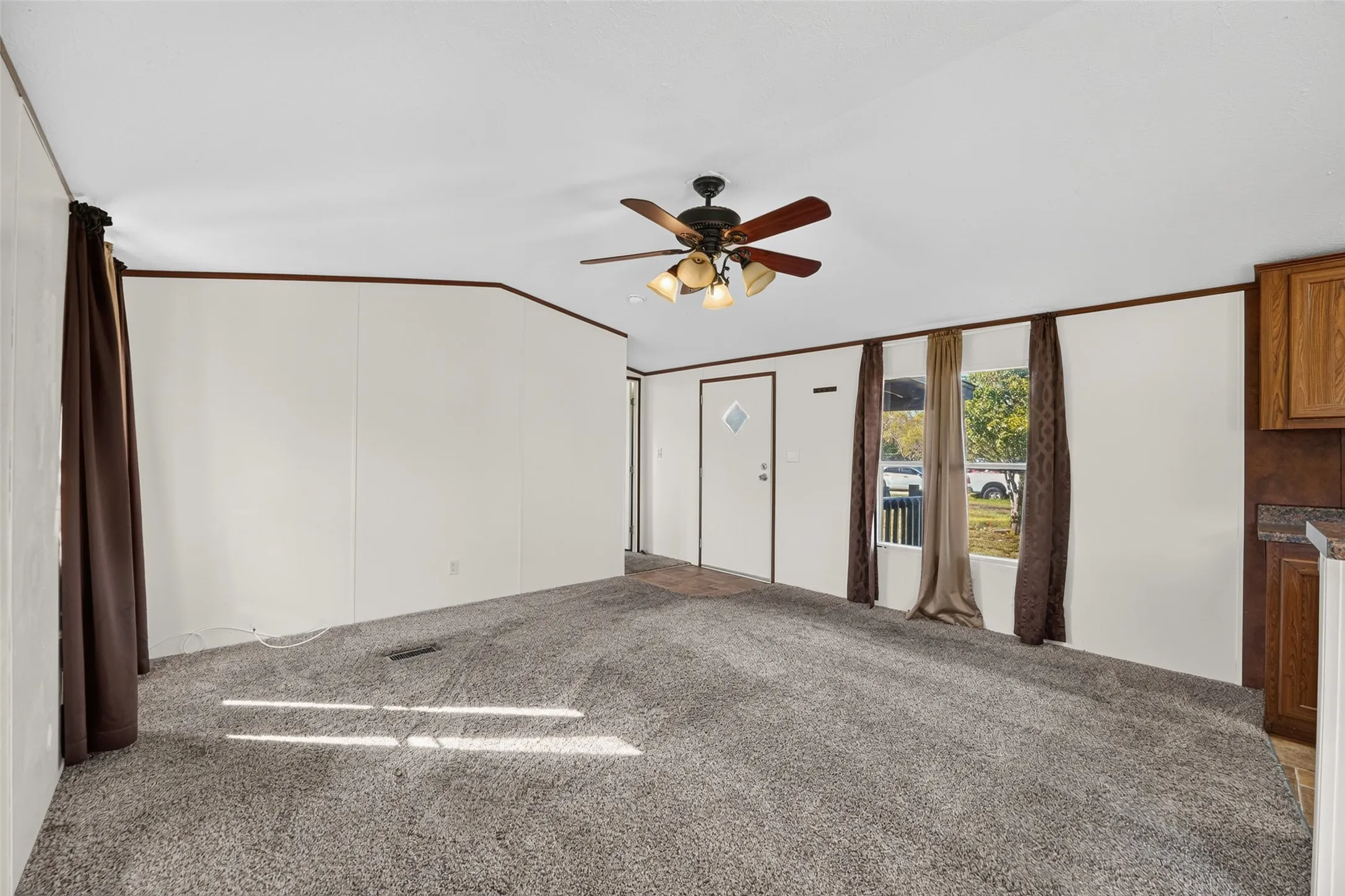 Carpeted flooring, white walls, and a ceiling fan with integrated lighting
