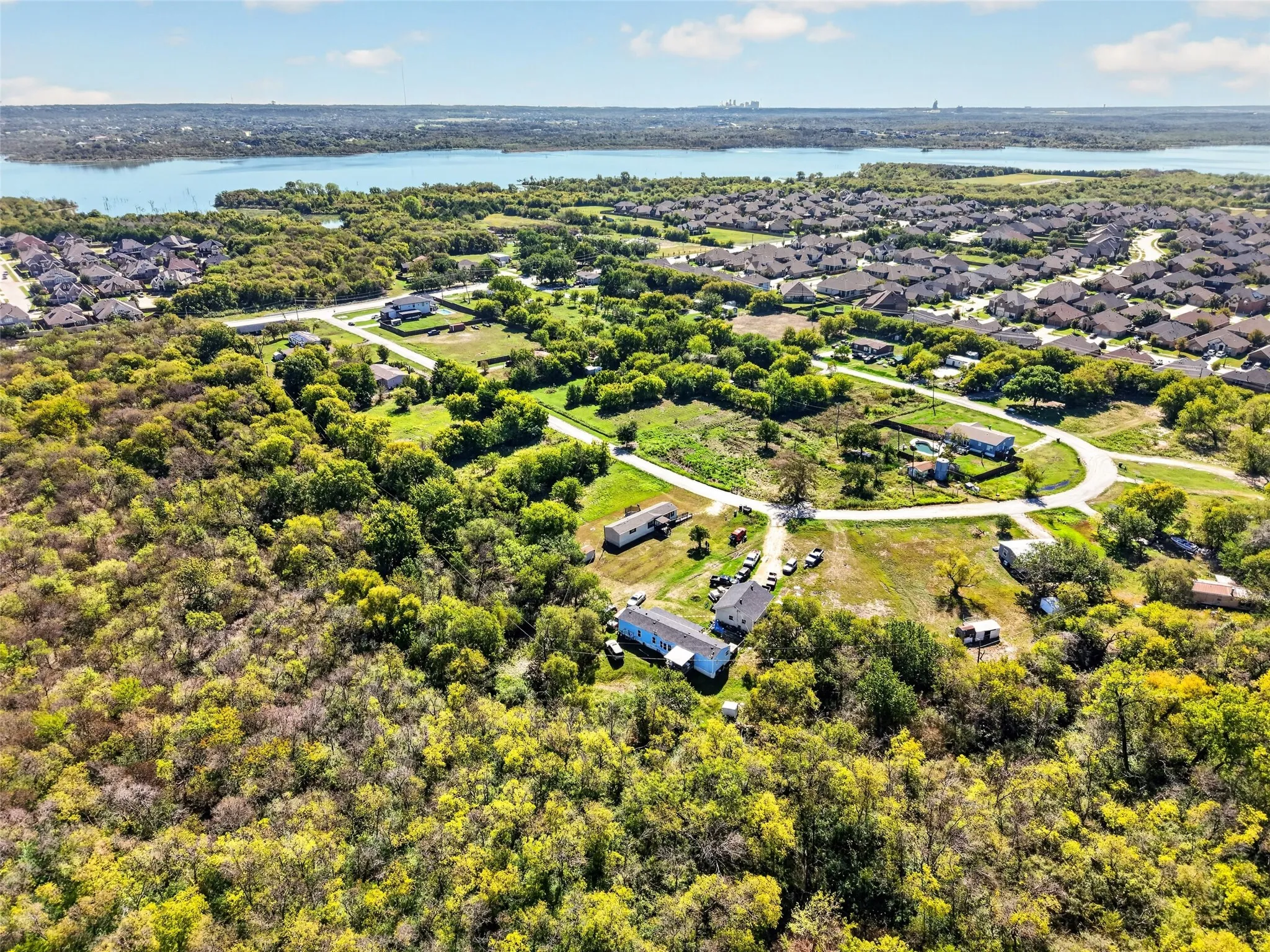 Expansive land parcel featuring dense tree coverage, open grassy areas, and a paved road