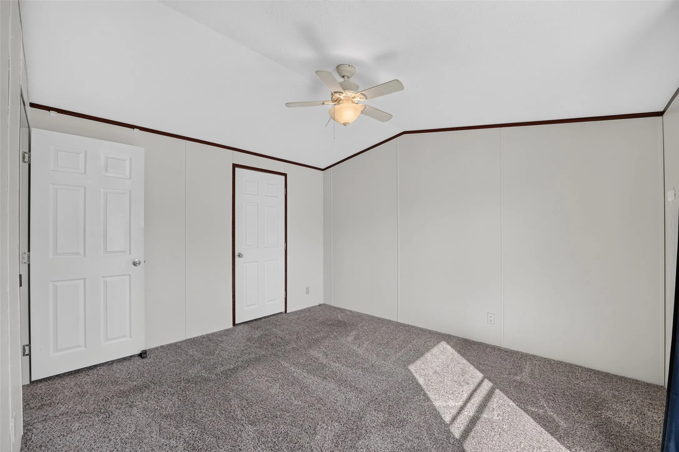 Plush carpeting, two paneled doors, and ceiling fan with integrated lighting