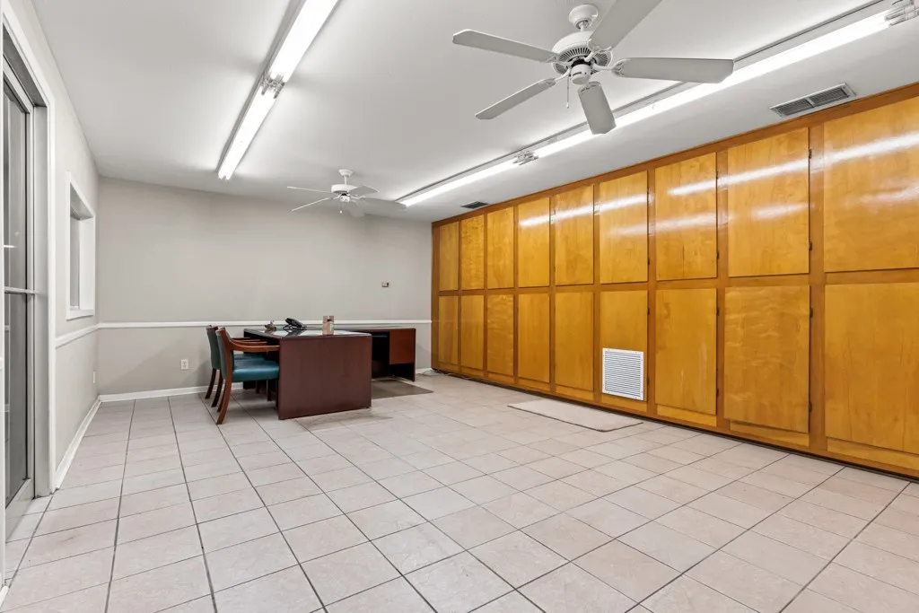Tile flooring, multiple ceiling fans, extensive built-in cabinetry, fluorescent lighting, and a window