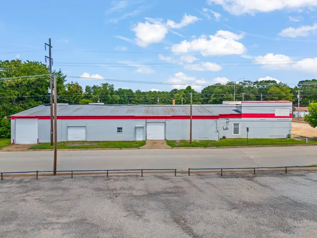 Light gray commercial building with a corrugated metal roof and red trim