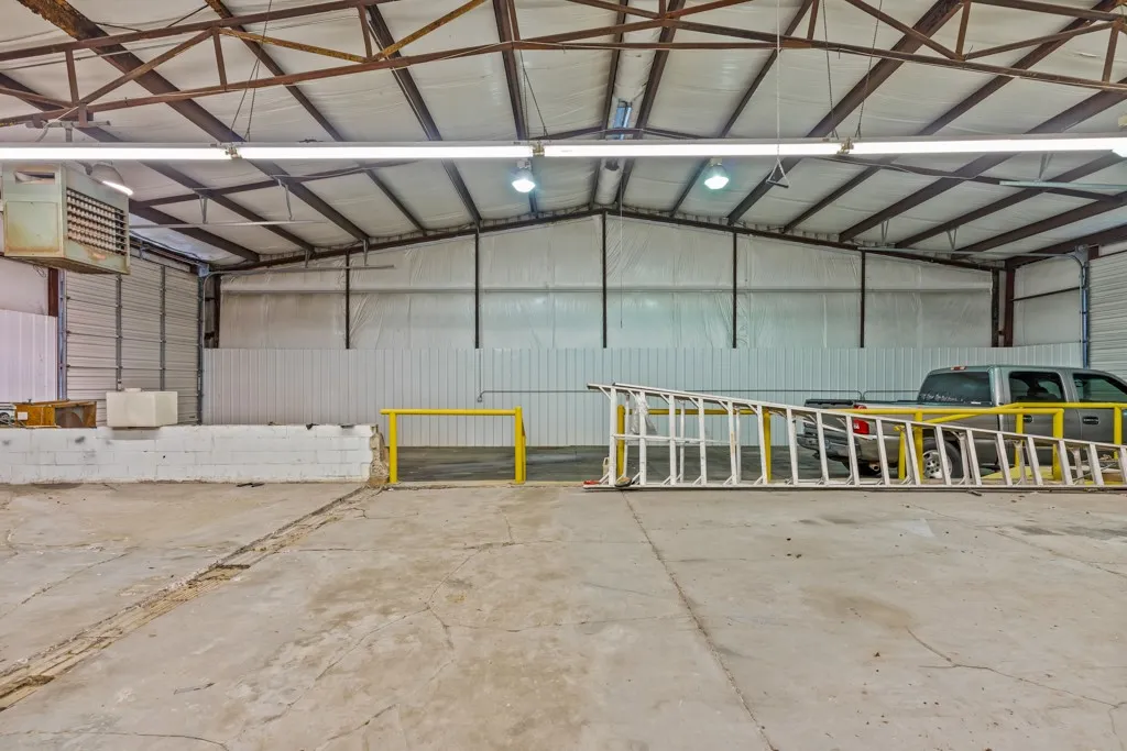 Large open warehouse space featuring concrete flooring and exposed metal beam ceiling