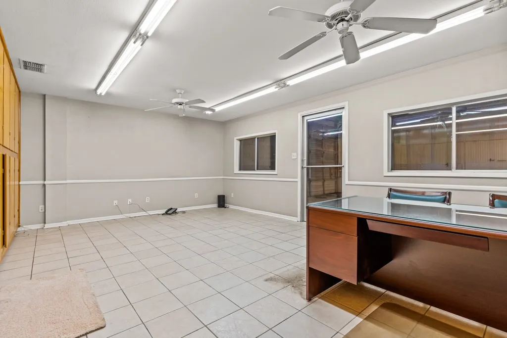 Tile flooring, built-in wooden cabinetry, multiple windows, fluorescent lighting, and ceiling fans