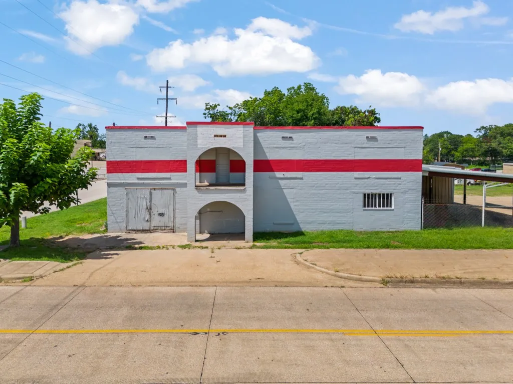 Single-story commercial building with a light gray and red painted brick exterior