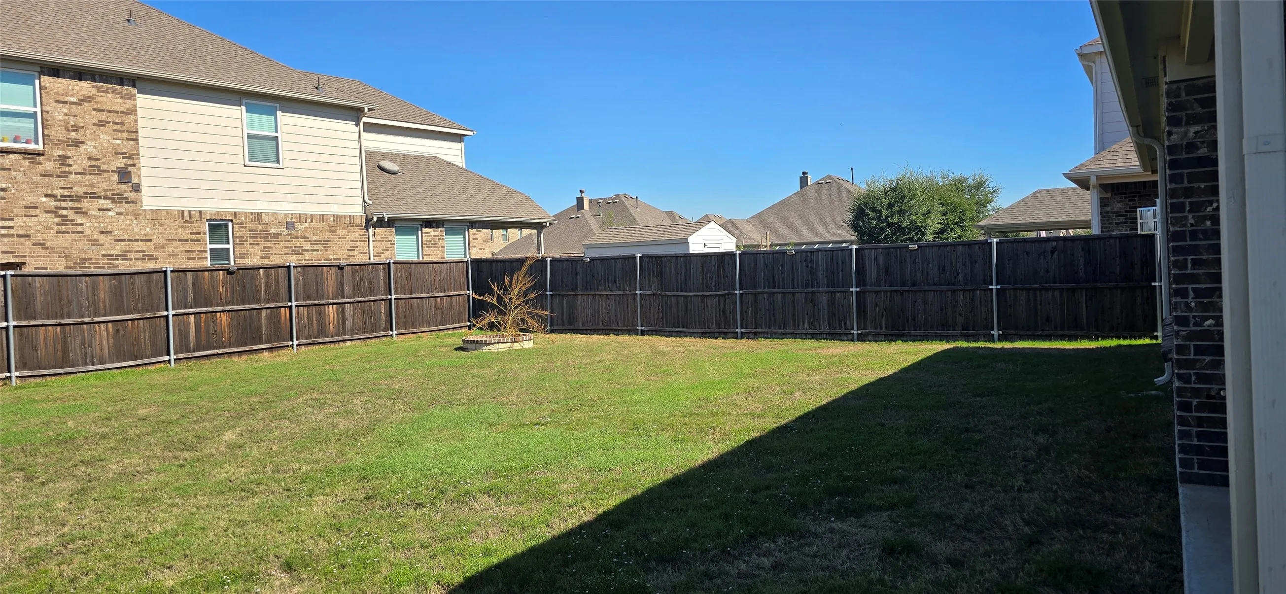 Expansive backyard with a full privacy fence, established lawn, and a small built-in planting area