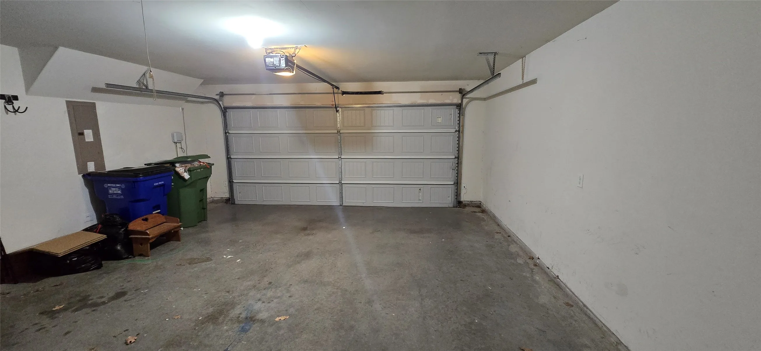 Attached garage with concrete flooring, finished walls, and an overhead garage door opener