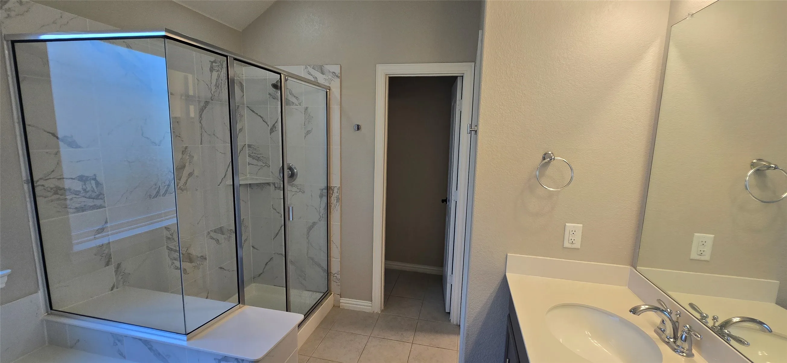 Shower with frameless glass enclosure and white-patterned tile surround