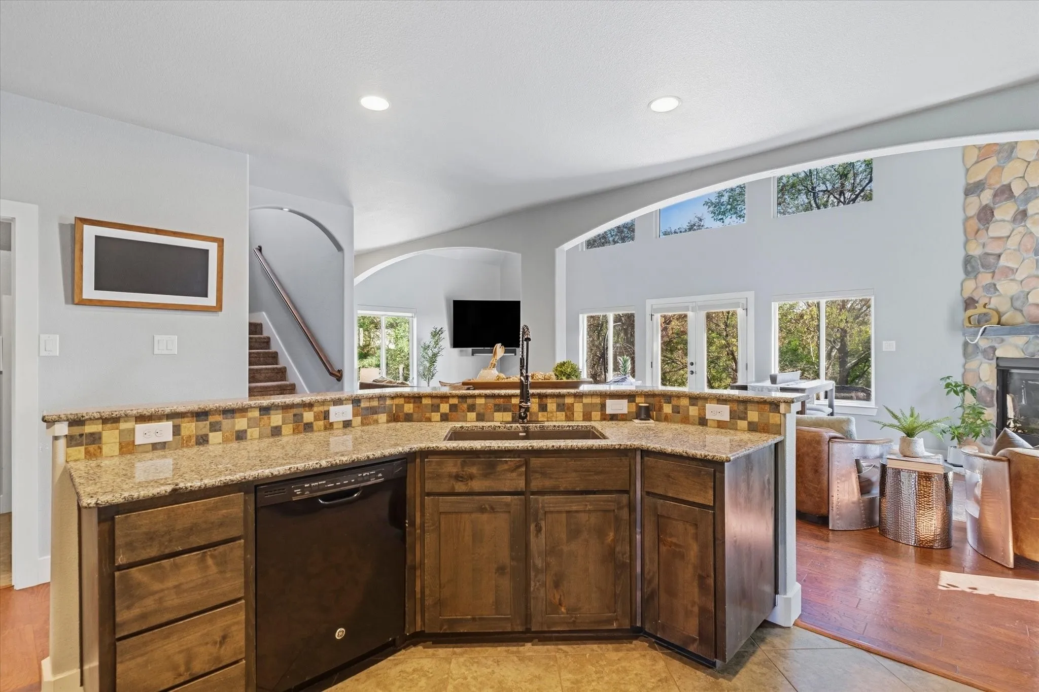 Kitchen with granite countertops, wood cabinetry, built-in dishwasher, and a tile backsplash