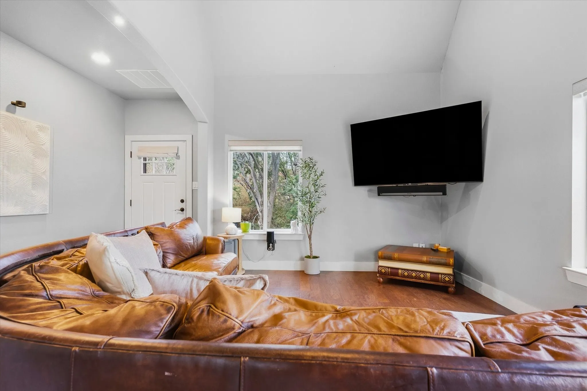 Wood-finish flooring, recessed ceiling lighting, light gray wall paint, white trim, and a white paneled entry door with window