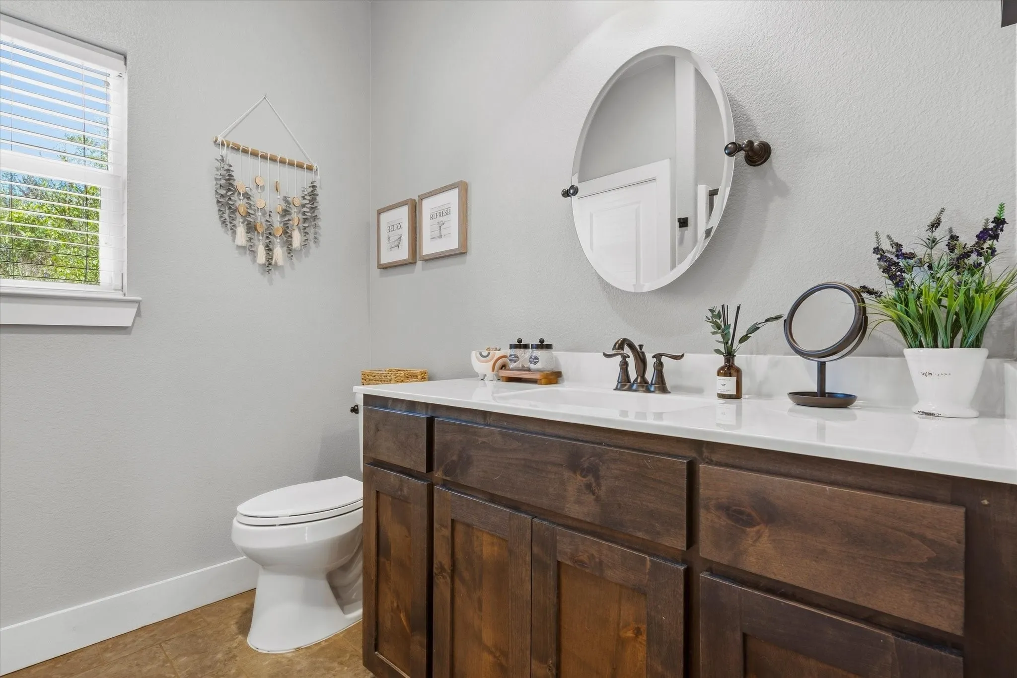 Bathroom featuring wood-finish cabinetry, white countertop, and an oval mirror