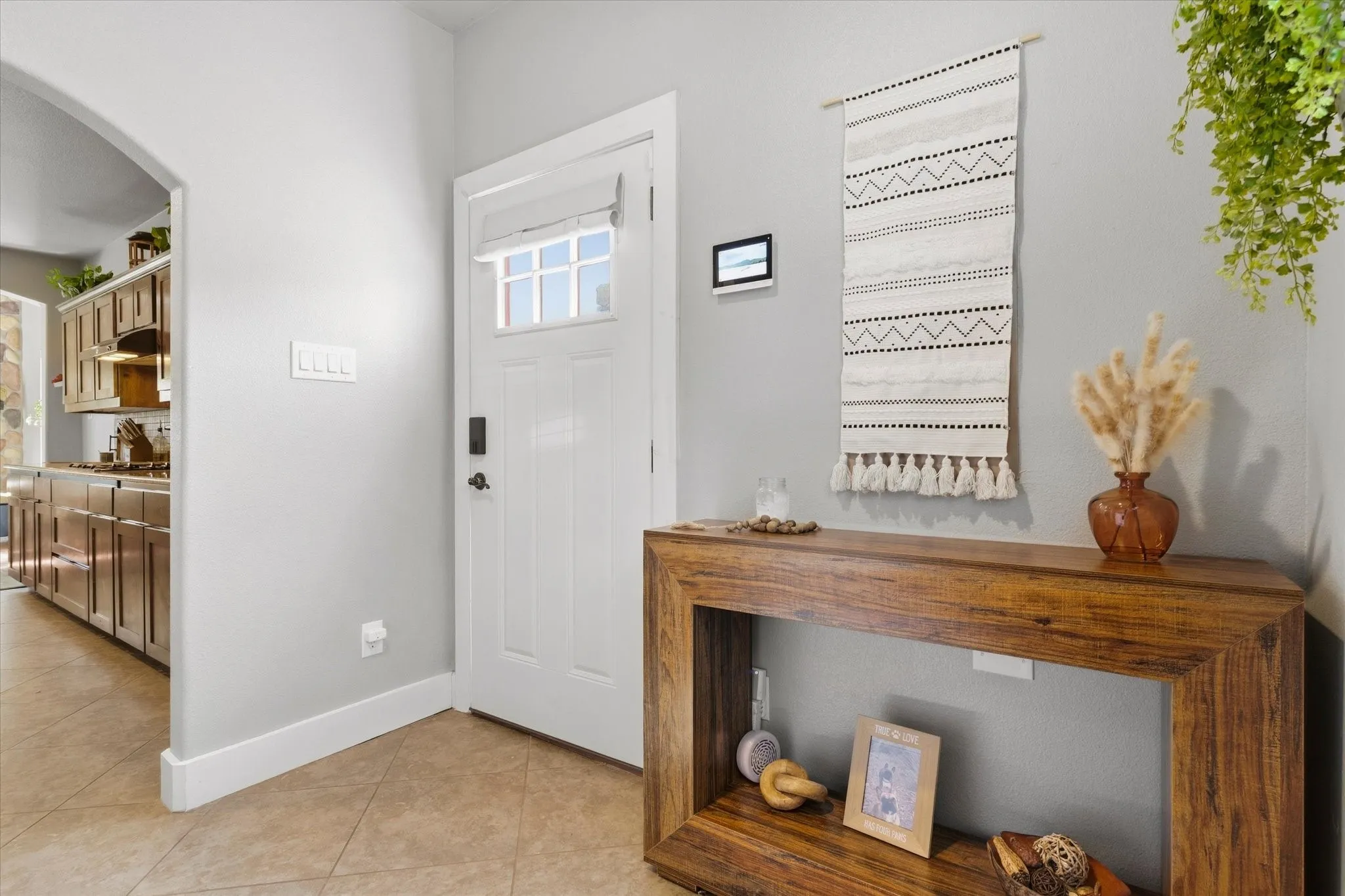 White paneled entry door with transom window, tile flooring, and wood-finish console table