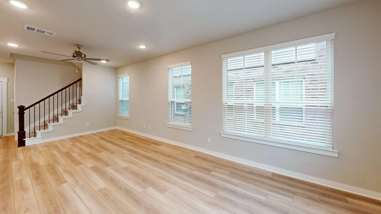 Wood-finish flooring throughout, multiple windows with blinds, recessed lighting, and a ceiling fan