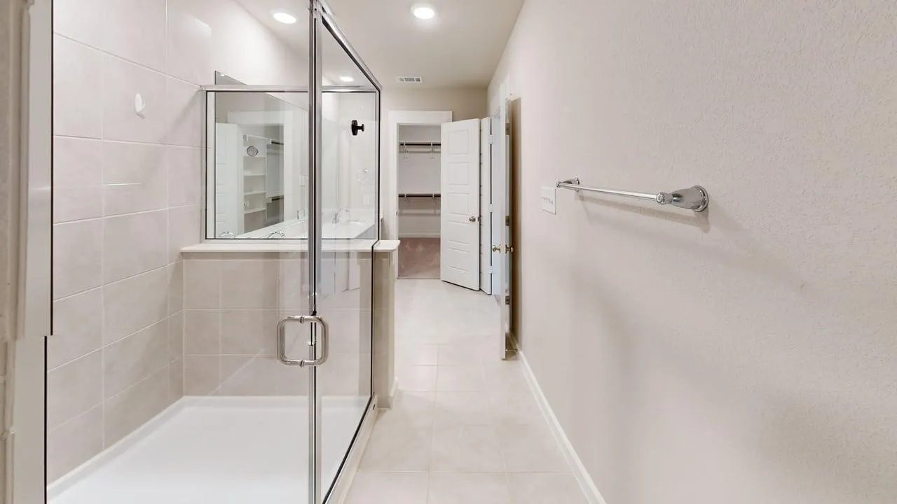 Glass-enclosed shower with a tiled surround, recessed lighting, and tile flooring