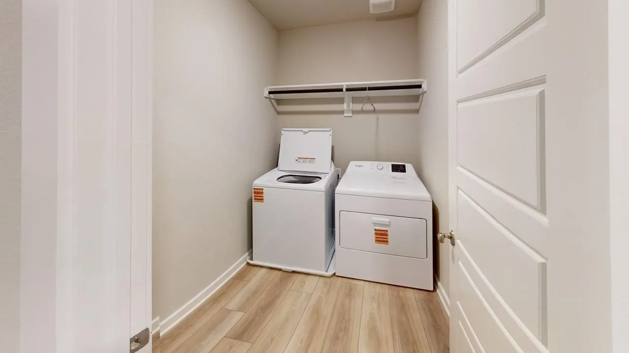Dedicated laundry area featuring wood-finish flooring and a built-in shelf