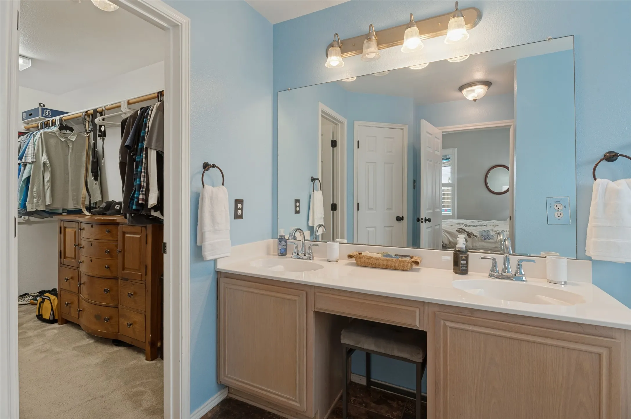 Double vanity with integrated sinks, light-toned cabinetry, and an expansive wall mirror