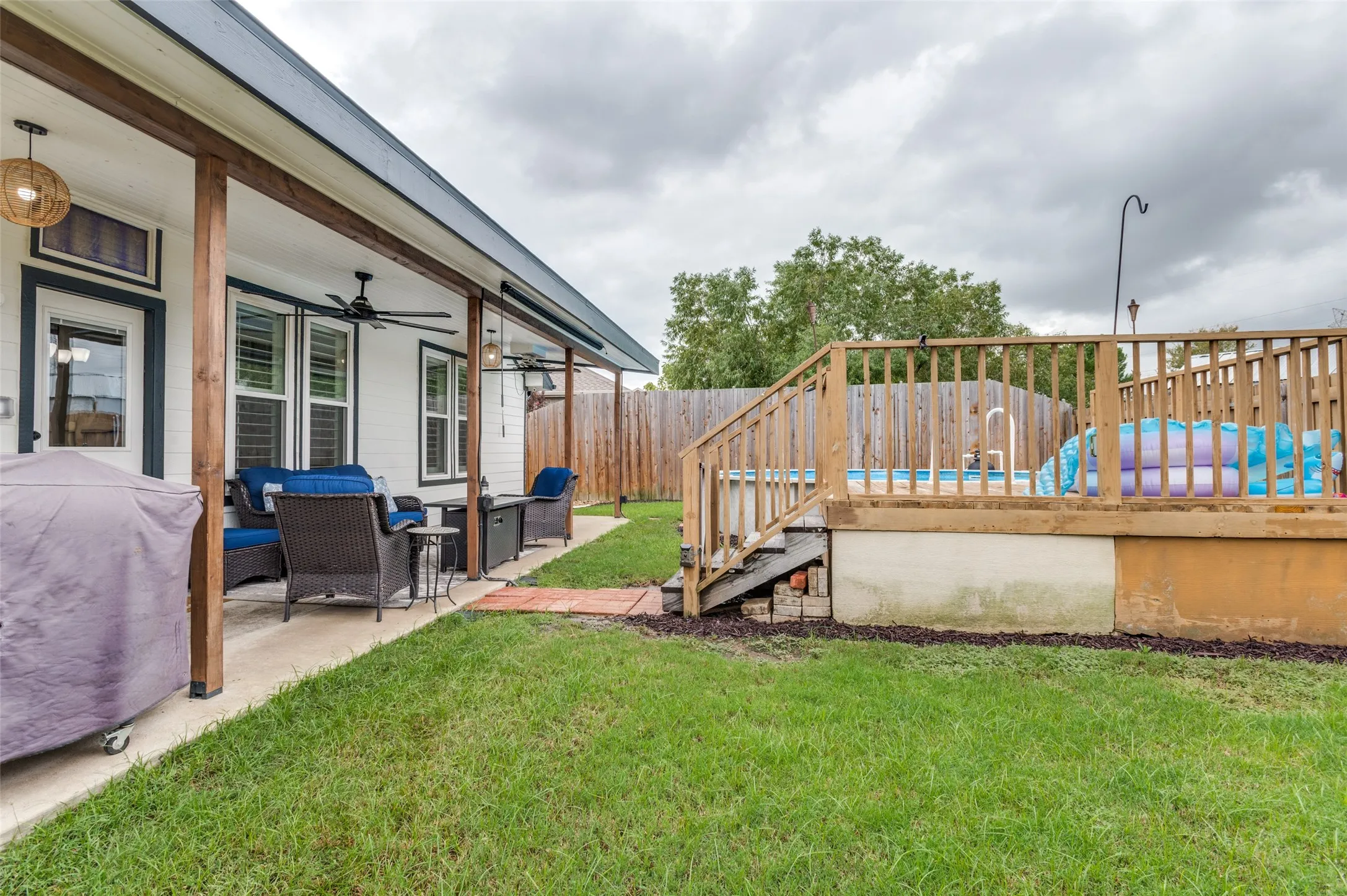 Covered patio with exposed wood beams, ceiling fans, and an adjacent wood-decked above-ground pool