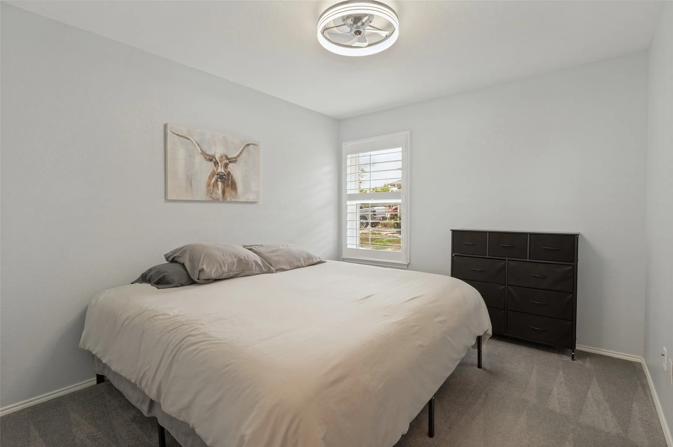 Recessed window with plantation shutters, light-toned walls, ceiling-mounted light fixture, and grey carpet