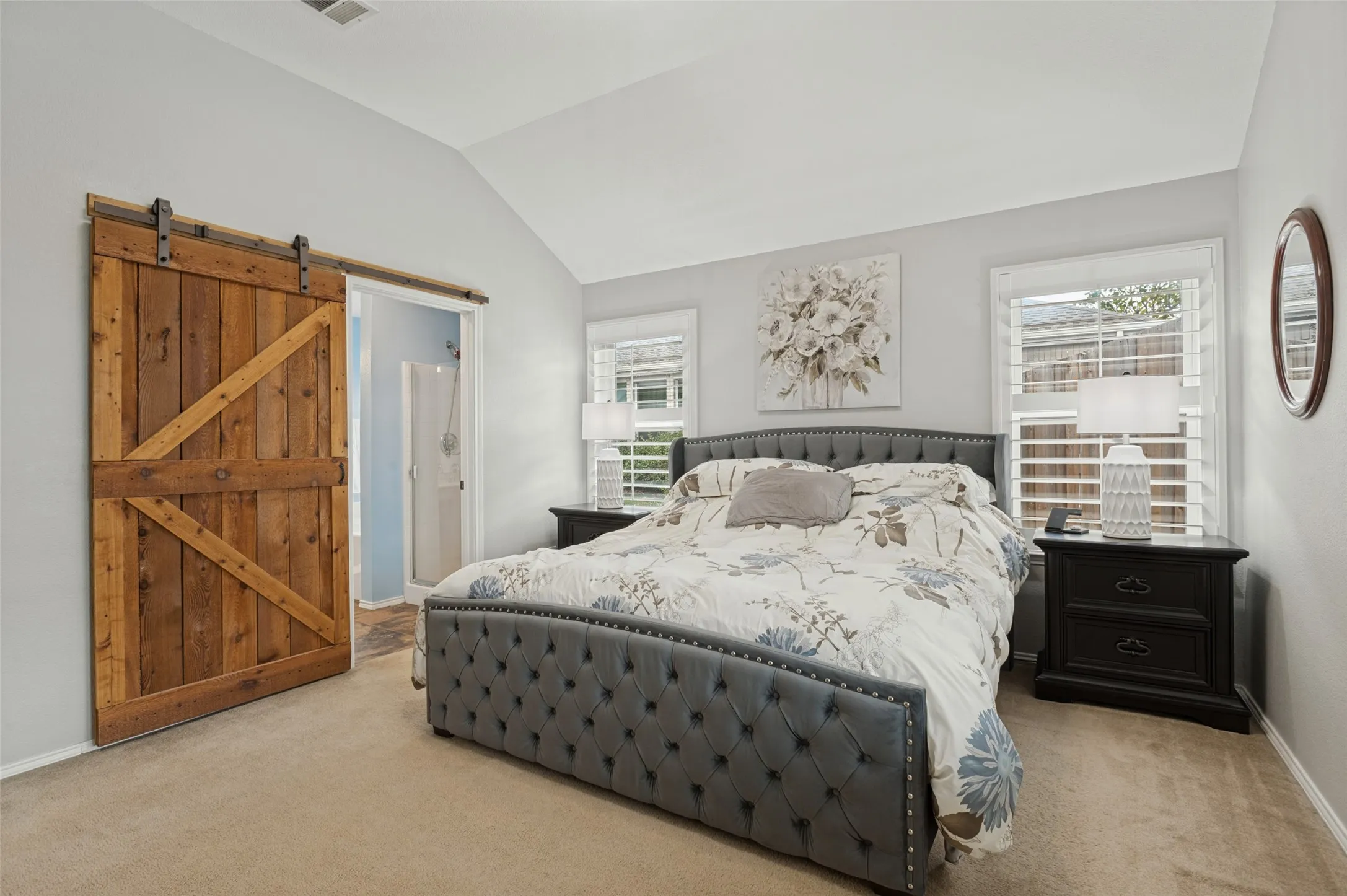 Vaulted ceiling, wood-finish barn door, and two windows with plantation shutters