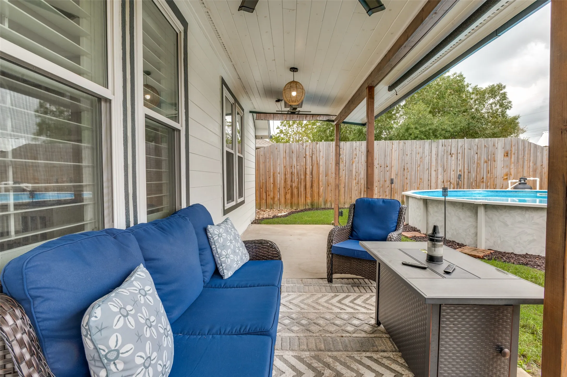 Covered patio with concrete flooring, wood privacy fence, and an above-ground pool