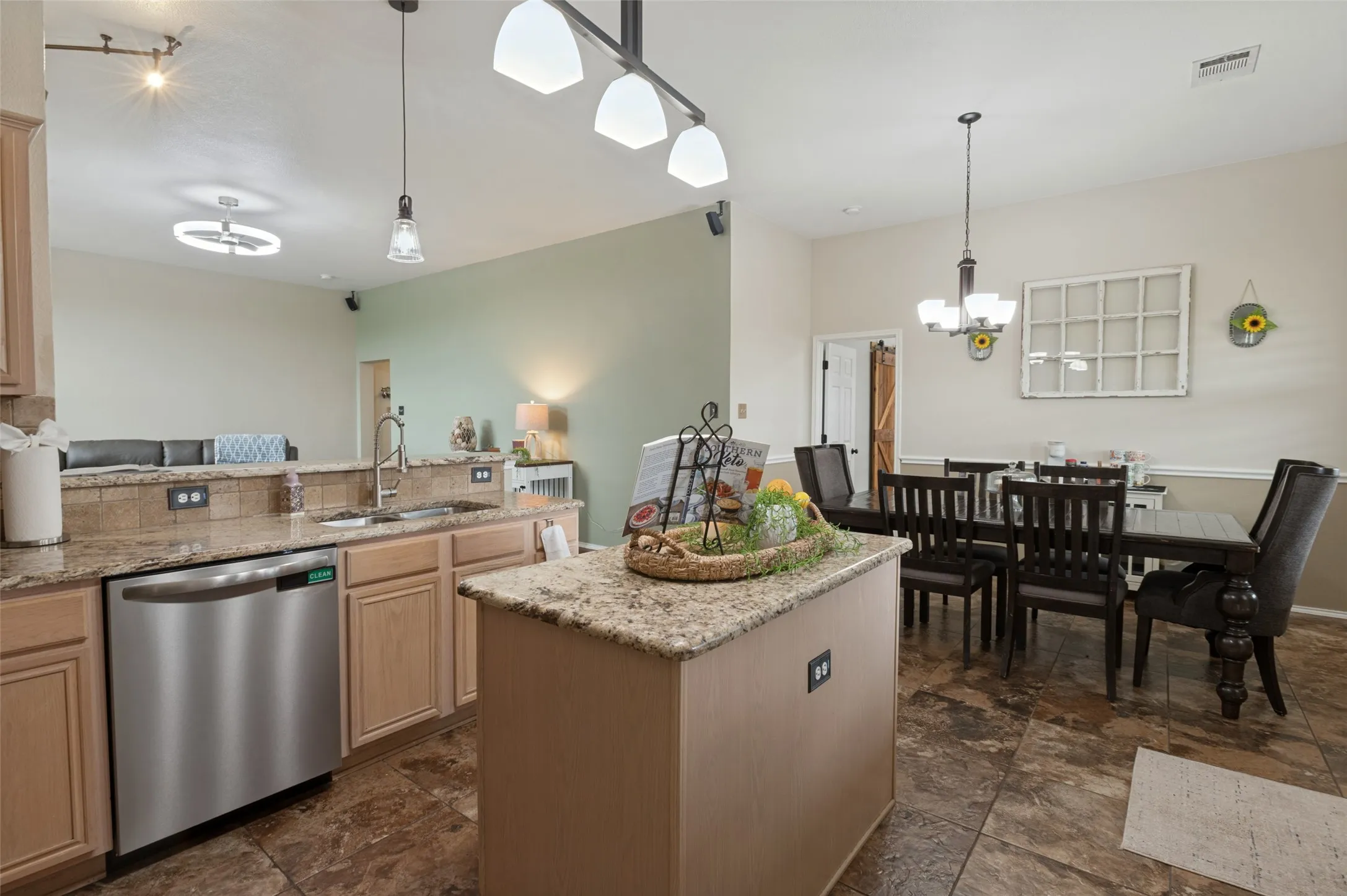 Kitchen featuring wood-finish cabinetry, stainless steel dishwasher, and granite countertops