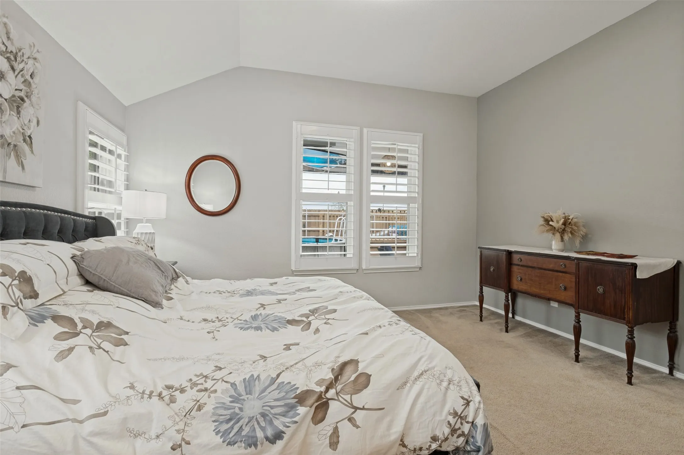 Vaulted ceiling with recessed lighting, two windows with plantation shutters, and carpeted flooring