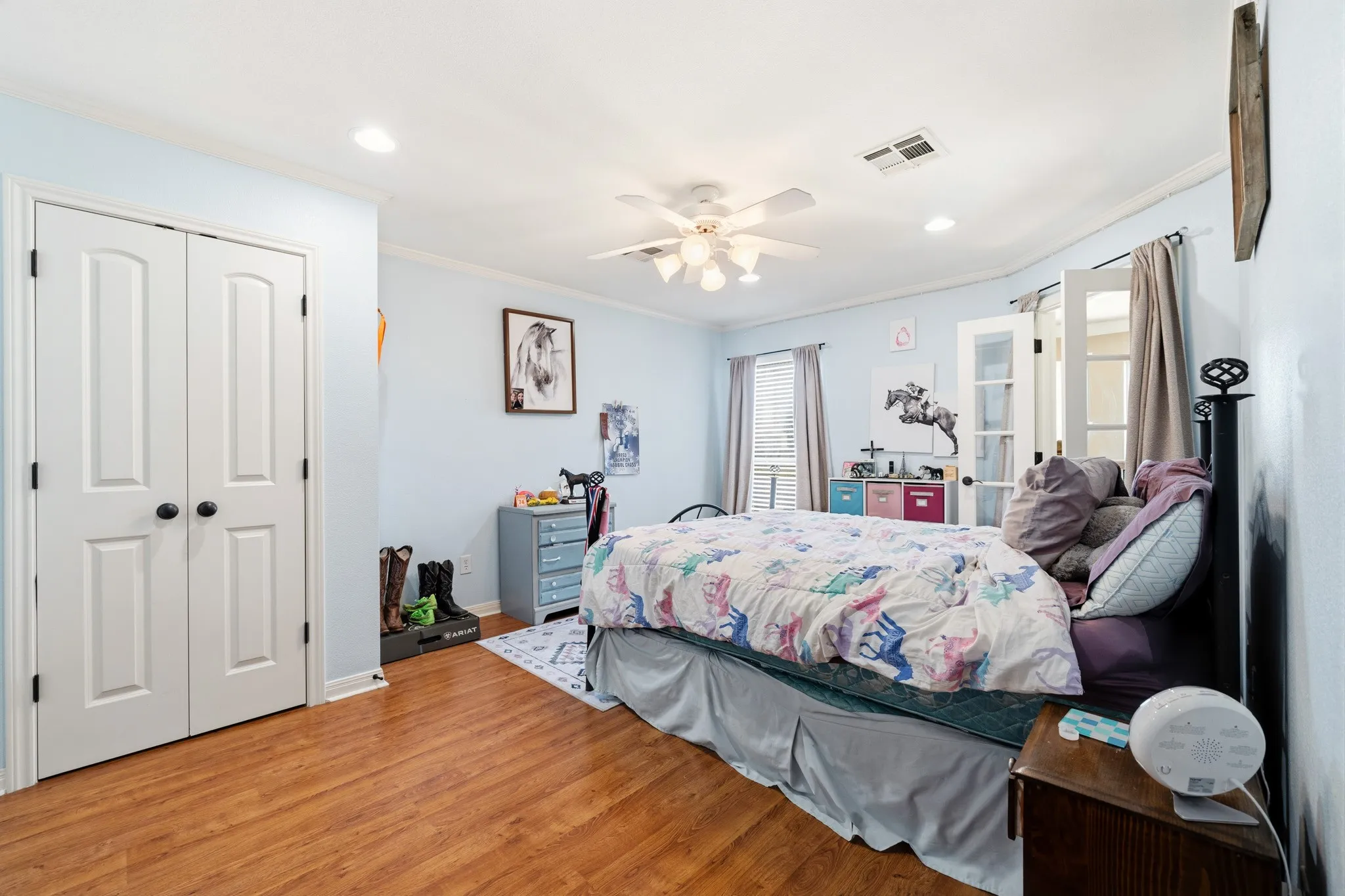 Wood-finish flooring, white bi-fold closet doors, recessed lighting, ceiling fan, and French doors
