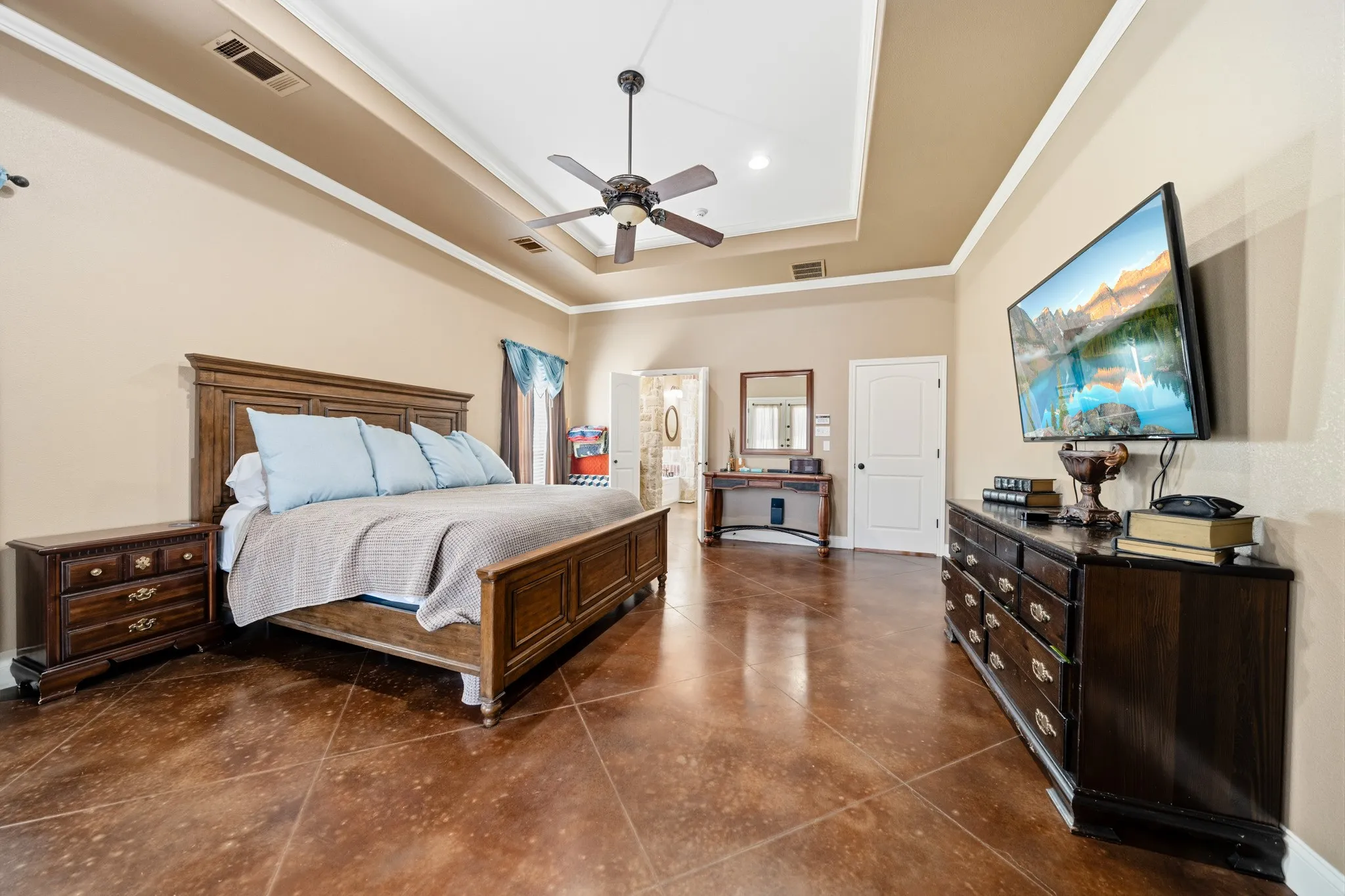 Tray ceiling with crown molding, ceiling fan, and tile flooring