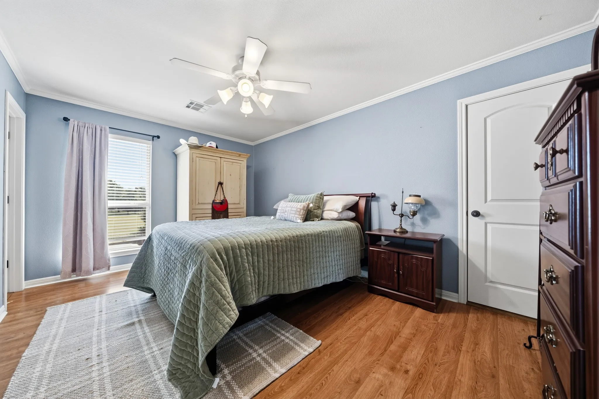 Wood-finish flooring, ceiling fan, white trim, and a window with blinds