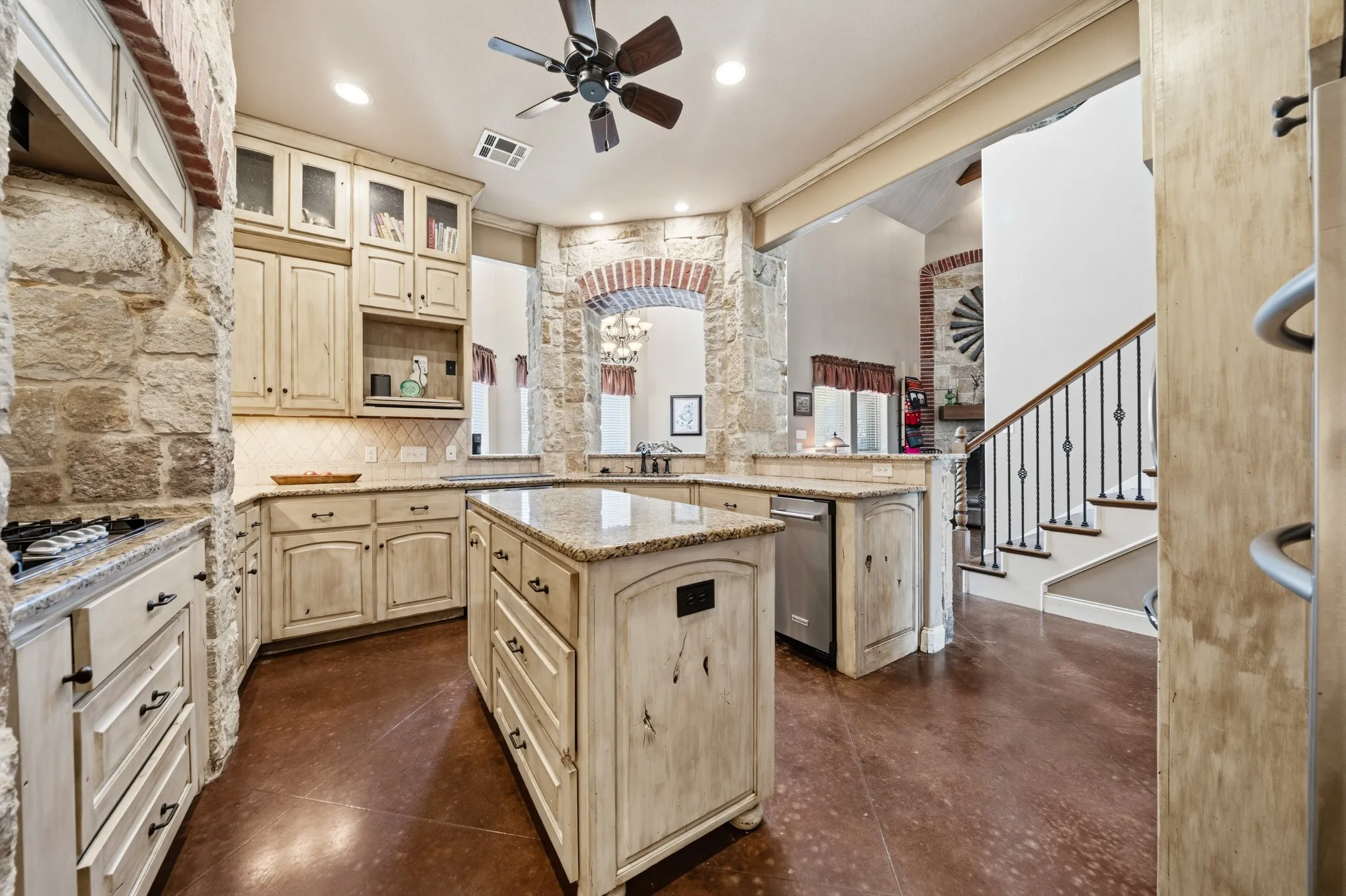 Kitchen featuring stone accent walls, a central island with a granite countertop, wood-finish flooring, recessed lighting, and a ceiling fan