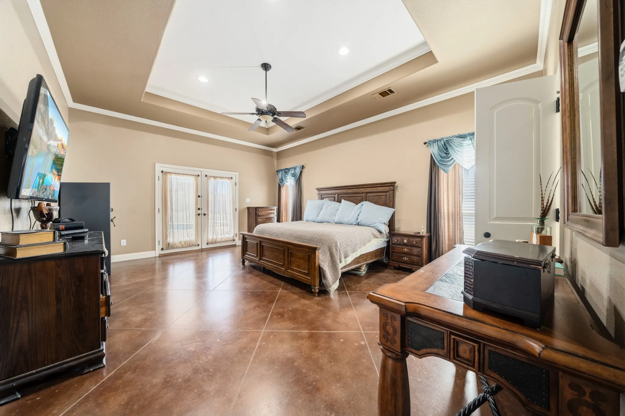 Tray ceiling with a ceiling fan, French doors, and polished concrete flooring