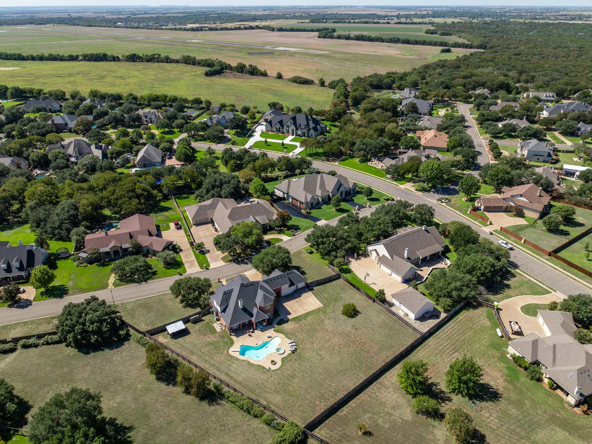 Residential neighborhood featuring multiple single-family homes, mature trees, and paved streets