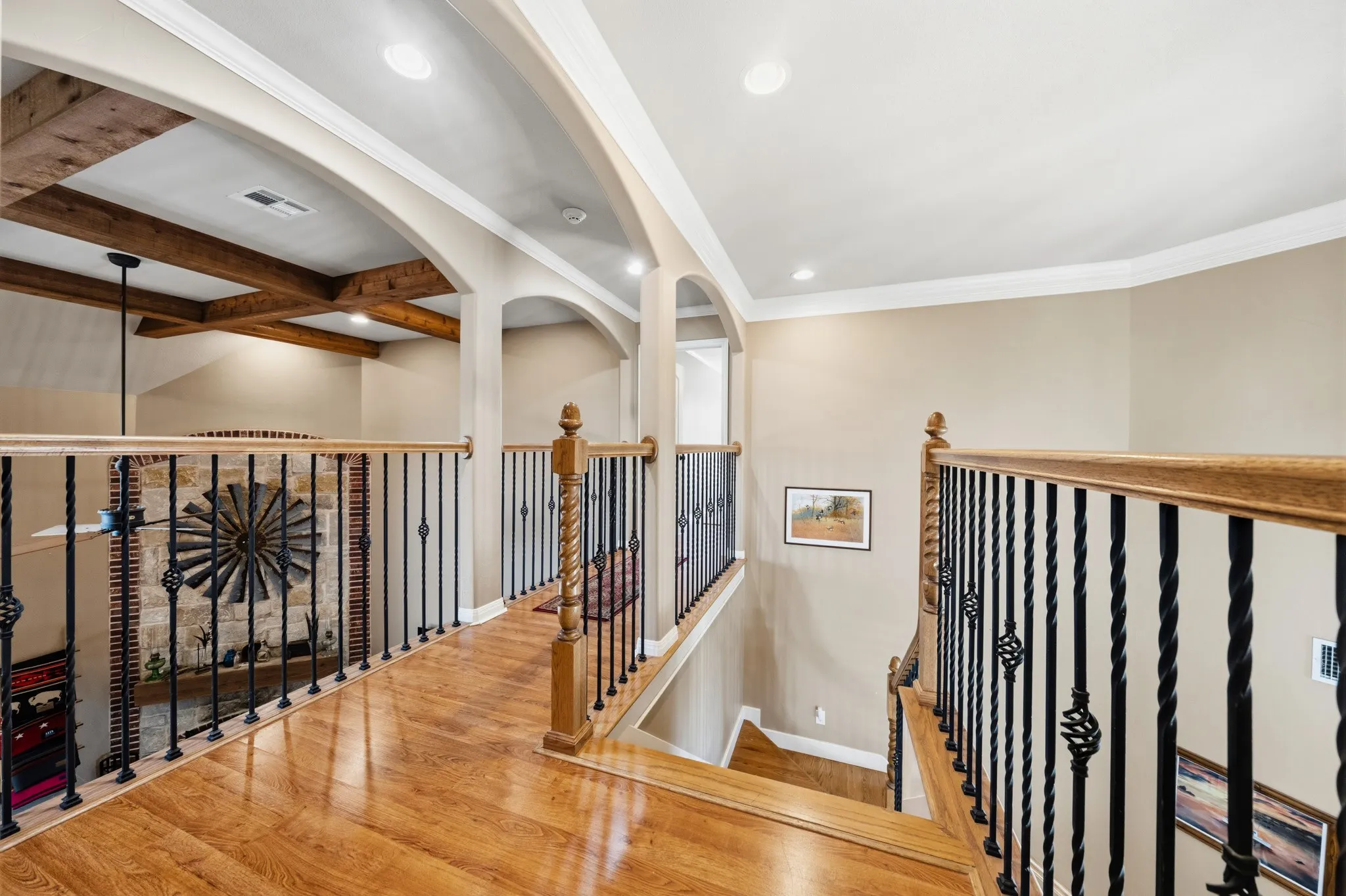 Wood-finish flooring, wrought iron balusters with wood handrails, recessed lighting, arched doorways, and exposed wood beams