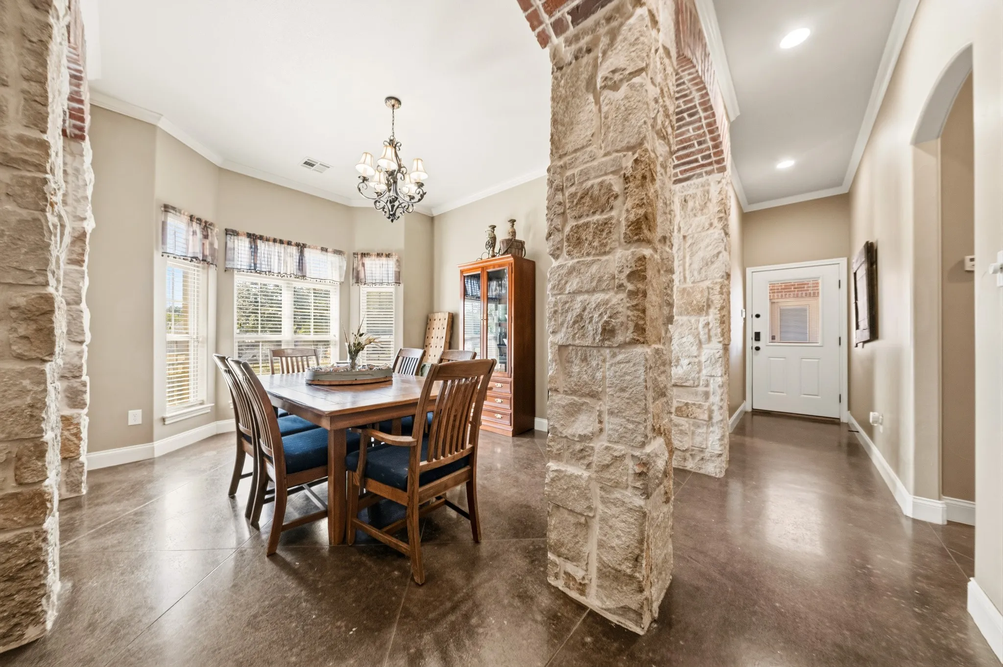 Stone archways, wood-finish flooring, recessed lighting, bay window, and a chandelier