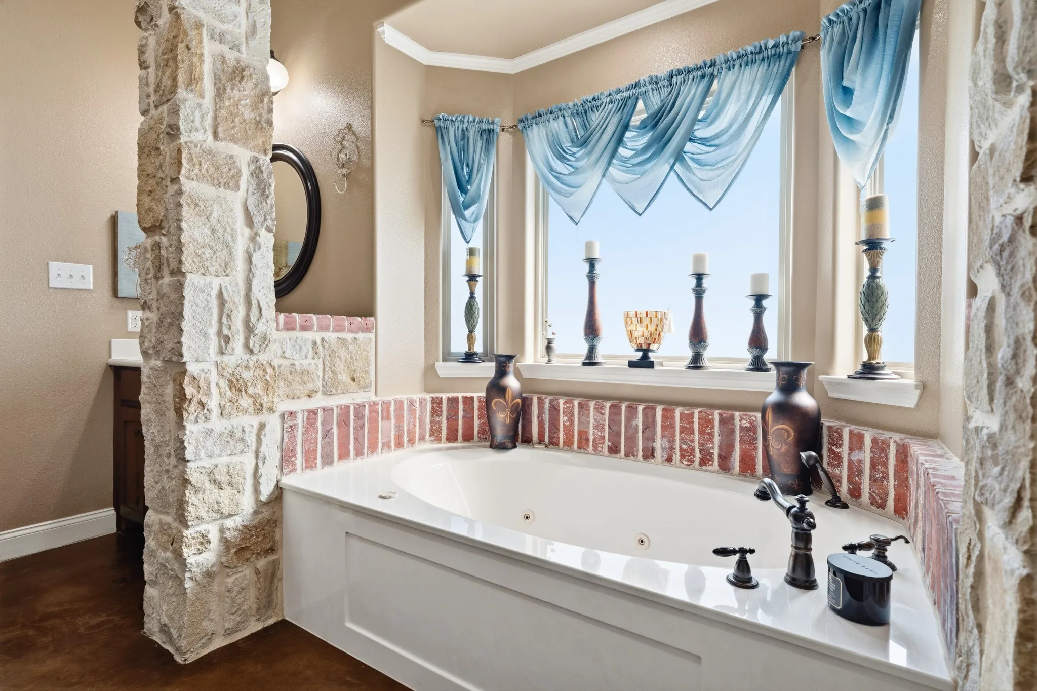 Built-in soaking tub with a corner window, brick-style surround, and stone accent wall