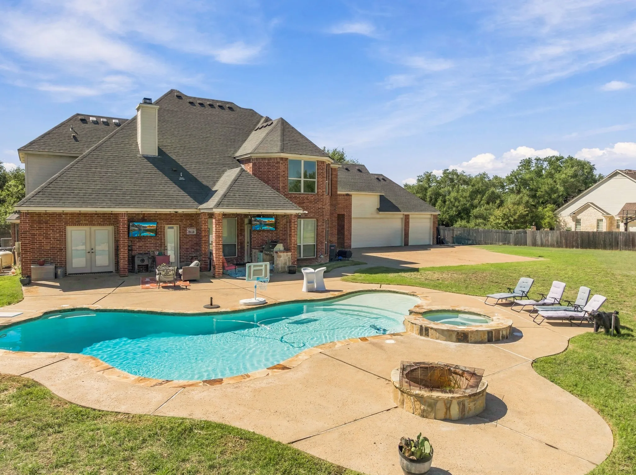 Brick exterior with a multi-level roofline, featuring a swimming pool, integrated spa, and a stone fire pit