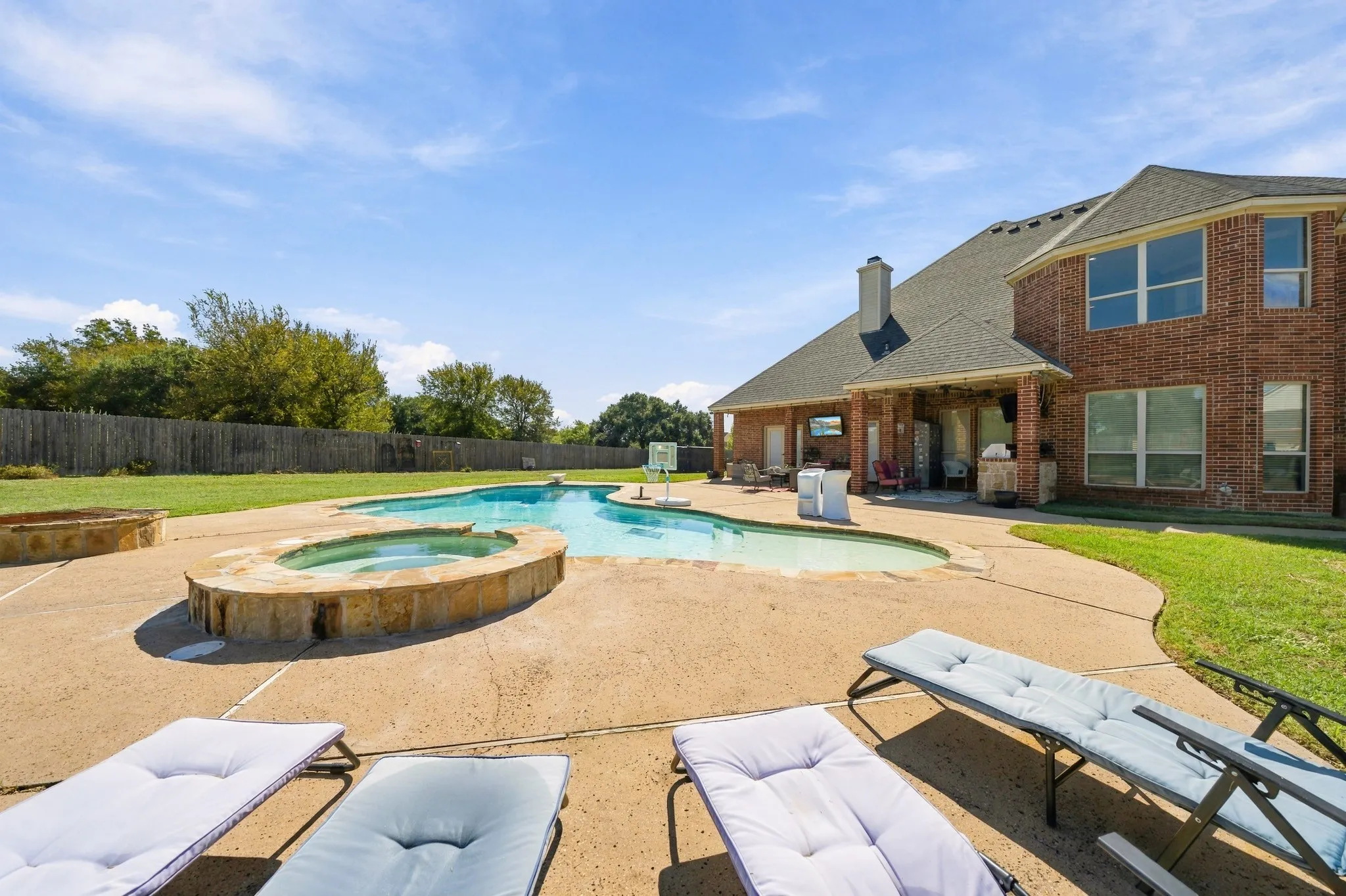 Custom freeform swimming pool with integrated spa and stone surround