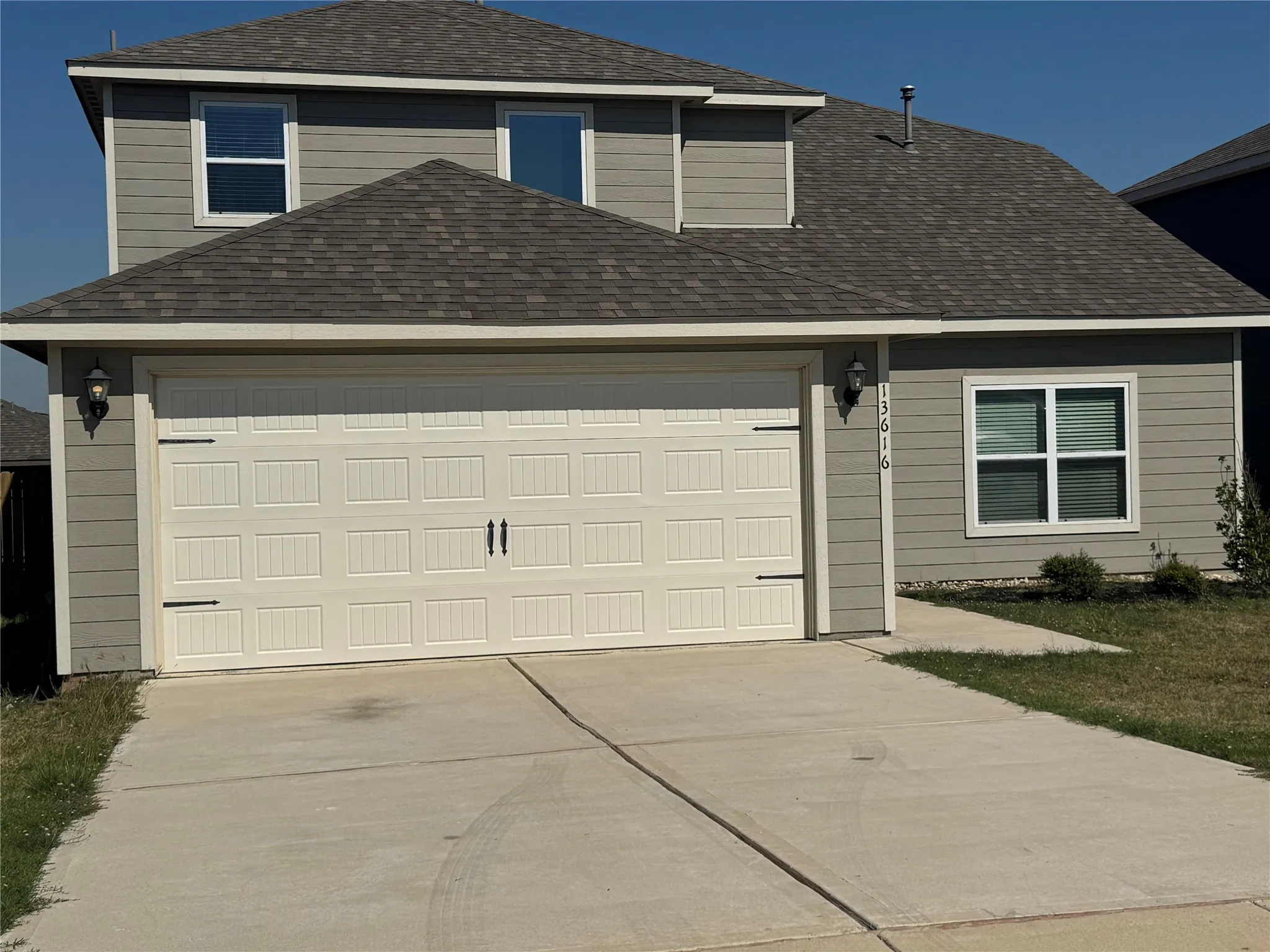 Two-story residence featuring horizontal siding, an attached two-car garage with decorative hardware, a concrete driveway, and a concrete walkway