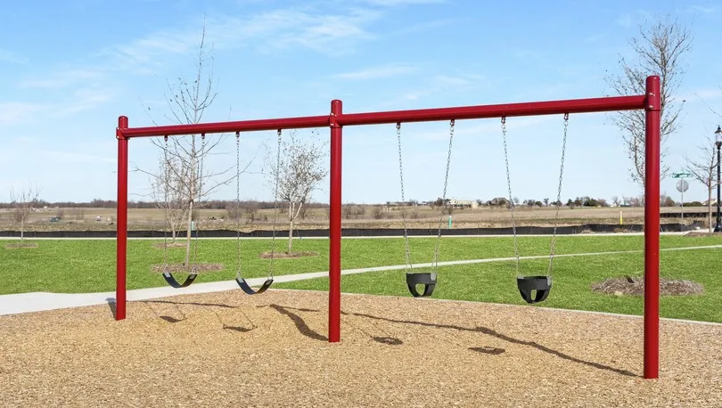 Outdoor swing set featuring red metal construction and rubberized seats