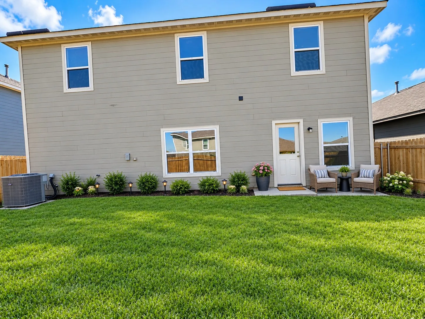 Expansive backyard featuring a manicured lawn, established landscaping, and a concrete patio