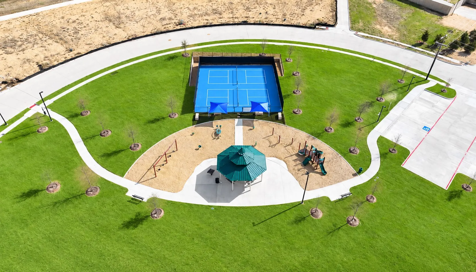 Community recreation area featuring a tennis court, a playground, a gazebo, and walking paths surrounded by extensive green space