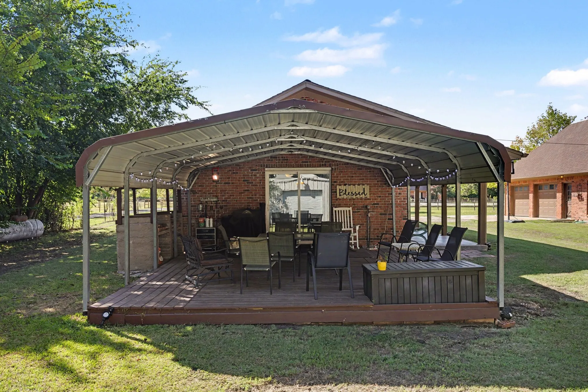 Covered back patio with a wood-finish deck and brick exterior