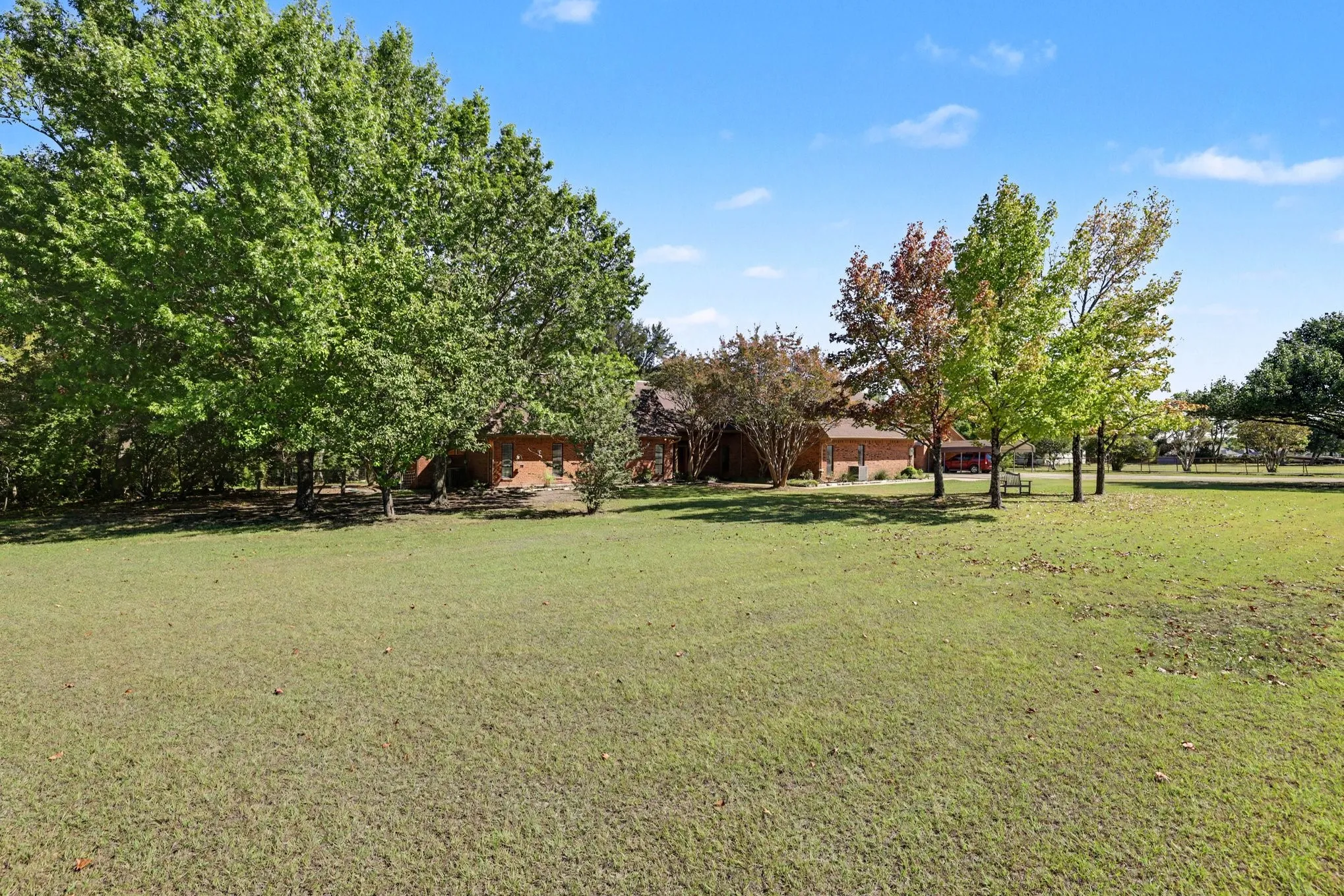 Expansive lawn area with mature trees and a brick-clad structure
