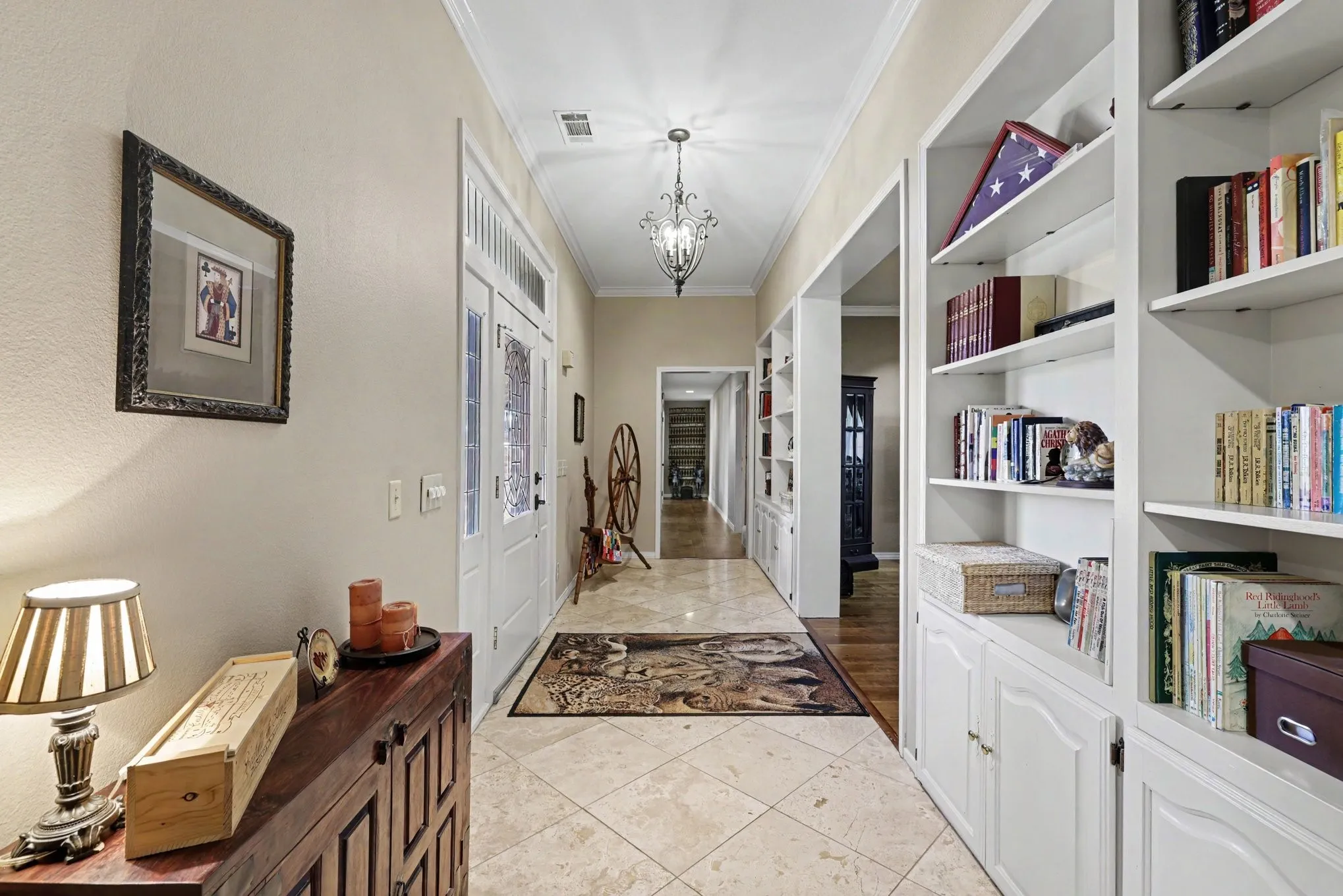 Hallway featuring tile flooring, built-in shelving, white paneled doors, and a decorative chandelier