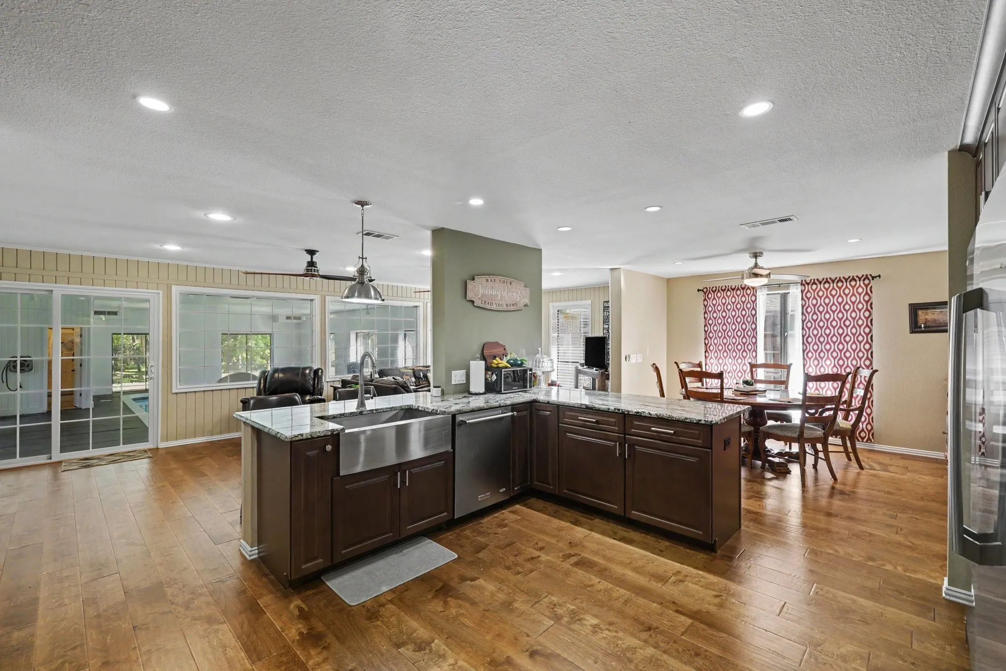 Kitchen island with an undermount farmhouse sink, granite countertops, and dark wood-finish cabinetry