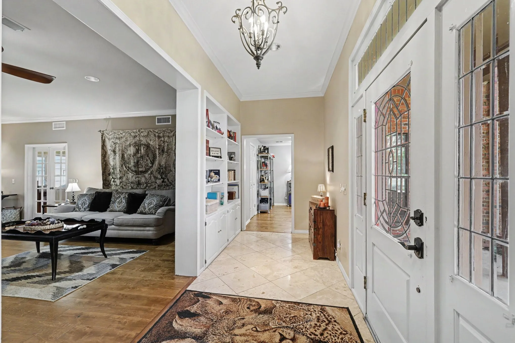 Entryway featuring leaded glass doors and side panels, decorative chandelier, built-in shelving, and tile flooring