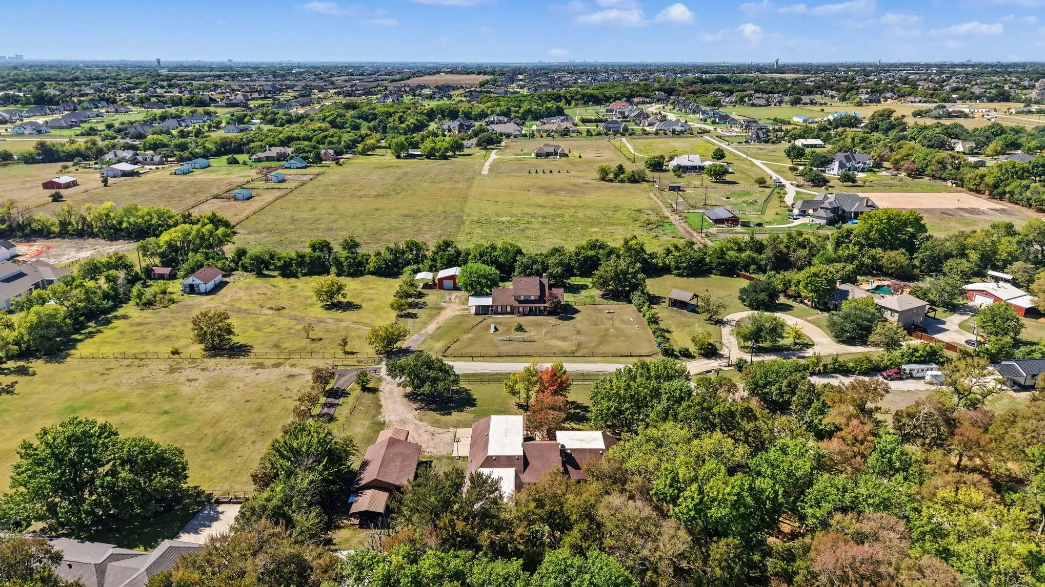 Expansive property with a central residence, multiple accessory structures, and extensive open land